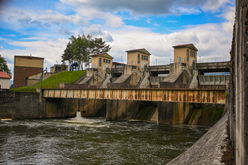 Water flows through hydroelectric dam spillway under cloudy sky, generating renewable energy