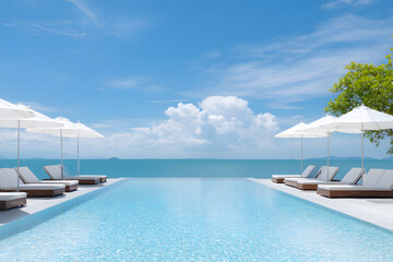 Obraz premium Luxurious infinity pool with sun loungers and umbrella overlooking the ocean