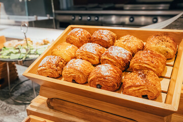Delicious pain au chocolat sprinkled with powdered sugar displayed on wooden crate in bakery, ready to be enjoyed
