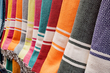 Vibrant and patterned traditional foutas hanging in a market stall, showcasing various colors and designs