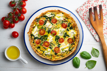 French quiche with spinach, cheese, tomatoes, and diced ham. Top view table with christmas decorations.