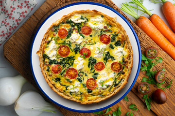 French quiche with spinach, cheese, tomatoes, and diced ham. Top view table with christmas decorations.