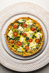 French quiche with spinach, cheese, tomatoes, and diced ham. Top view table with christmas decorations.