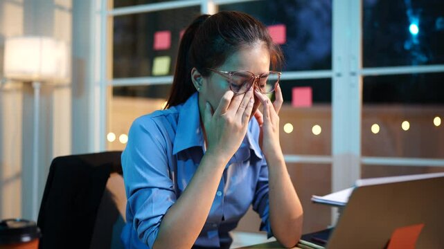 An ambitious Asian businesswoman works late at her desk, focused on sales, planning, and analysis under tight deadlines in a modern office.