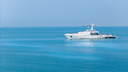 Aerial view of a modern patrol vessel sailing on calm turquoise sea, equipped with radar, deck equipment, and a helipad. Concept of maritime security, naval operations, and coast guard missions.