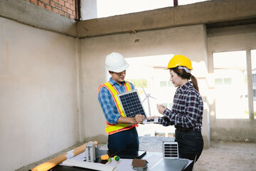 Architects and engineers collaborate at a desk with blueprints and solar panels, planning...
