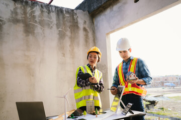 Architects and engineers collaborate at a desk with blueprints and solar panels, planning...