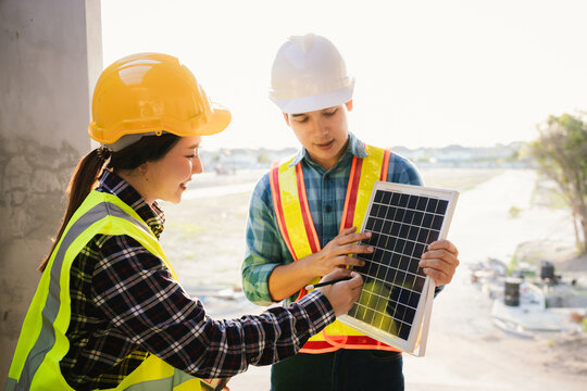 Architects and engineers collaborate at a desk with blueprints and solar panels, planning sustainable energy solutions for eco-friendly construction projects.
