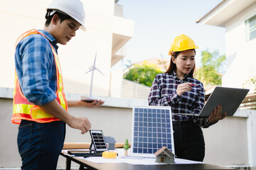 Architects and engineers collaborate at a desk with blueprints and solar panels, planning...