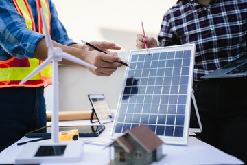 Architects and engineers collaborate at a desk with blueprints and solar panels, planning...