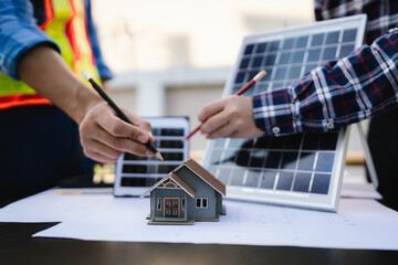 Architects and engineers collaborate at a desk with blueprints and solar panels, planning...