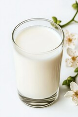 Fresh milk served in a clear glass with floral accents on a white surface showcasing a simple and elegant presentation