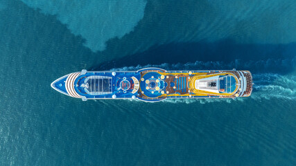 Aerial top view of a luxury cruise ship sailing through deep blue ocean water. Vibrant deck design...