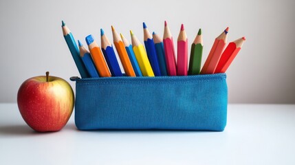 Naklejka premium Back to School Still Life with Apple and Colored Pencils in Blue Case on White Tabletop in Studio Setting