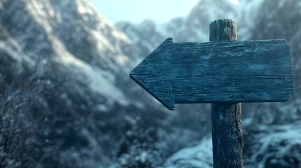 A wooden arrow sign pointing to the left on an old blue wooden table with blurry snow-capped mountains in the background