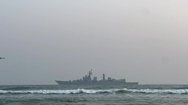 INS Satpura sailing in waving sea with helicopters.