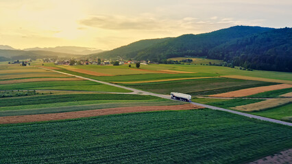 Aerial view of a truck transporting cargo through a lush green field, symbolizing efficient...