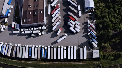 Aerial view of a bustling parking lot filled with rows of trucks and cars, symbolizing efficient transportation and cargo distribution.