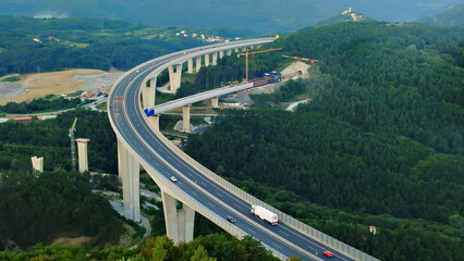 Aerial view of a winding highway with a truck and car, symbolizing efficient cargo transportation...