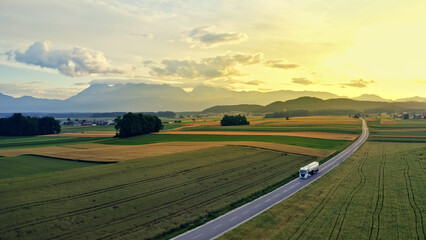 Aerial view of a truck driving down a winding road through vast fields, symbolizing efficient cargo...