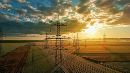 Aerial view of power lines and towers in a vast field, symbolizing the interconnectedness and reach of energy infrastructure.