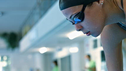 Athlete's focused expression and goggles in a pool setting convey dedication and intensity in swim...