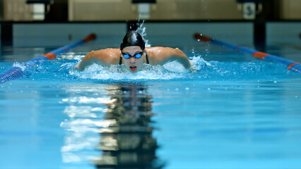 Athlete glides through the pool, demonstrating focus and skill in an indoor swimming training session.