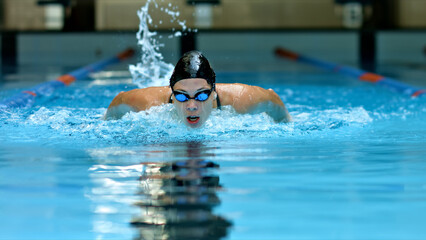 Athlete glides through the pool, water splashing around, highlighting intense focus and dedication...