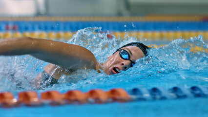 Athlete glides through water, demonstrating strength and technique in indoor swimming. The close-up shot captures the intensity and focus of competitive swim training.