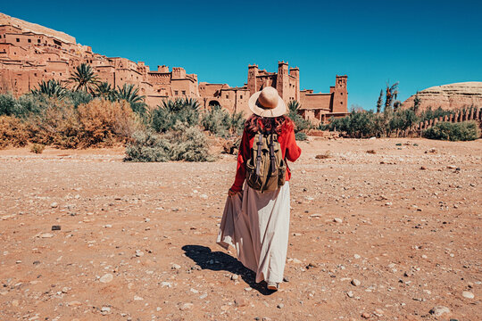 Female tourist walking towards Ait Benhaddou, an ancient fortified city - ksar - in Morocco, on a sunny day