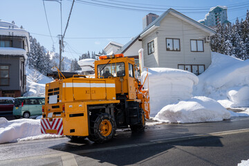 Bright orange snow removal vehicle parked on a snowy residential street in winter. The powerful...