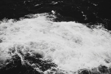 Foamy white water erupts from dark sea.  Detailed view of waves crashing