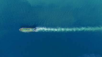 Obraz premium Aerial view of an oil tanker ship sailing through calm blue ocean water, leaving a visible white wake behind. Concept of global transportation, marine logistics, and energy shipping.