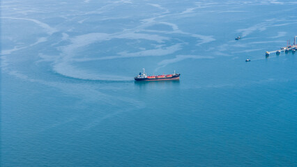 Naklejka premium Aerial view of an LPG tanker ship navigating calm blue waters near an offshore terminal. Ideal for themes on energy transport, maritime industry, and international gas shipping.