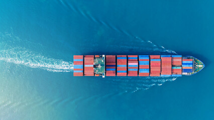 Aerial top view of a large cargo ship fully loaded with colorful shipping containers navigating...