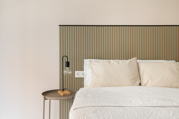 Bedroom with close up view of bed white bedding beige pillows ribbed green headboard and round side table