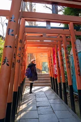 Fotobehang Torii Gates Tourist walking through a tunnel of traditional red torii gates at a Japanese shrine, symbolizing a spiritual journey and cultural heritage in Japan’s sacred architecture.  © Yellow Boat