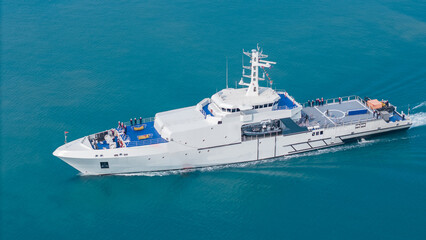 Aerial view of a modern patrol vessel sailing on calm turquoise sea, equipped with radar, deck equipment, and a helipad. Concept of maritime security, naval operations, and coast guard missions.