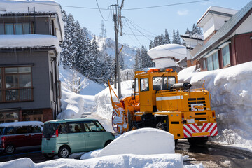 Bright orange snow removal vehicle parked on a snowy residential street in winter. The powerful...