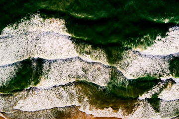 Aerial view Top down Waves crashing on sandy shore,Dark sea surface in summer day background,Seascape top view waves at Phuket Thailand