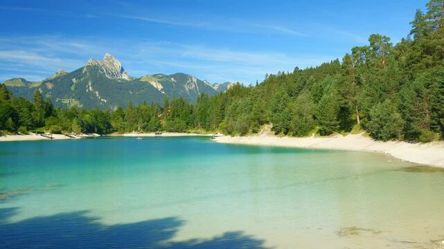 Clear alpine lake Urisee in Reutte Tyrol with turquoise water, quiet shorelines, and forest-covered hills in a summer vacation mood