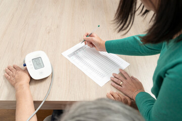Nurse writing down blood pressure reading from a tensiometer on a medical chart