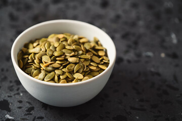pumpkin seeds in white bowl on terrazzo countertop