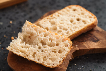 ciabatta bread sliced in half for sandwich on olive board