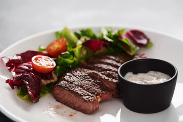 ribeye steak with garlic sauce and fresh salad closeup