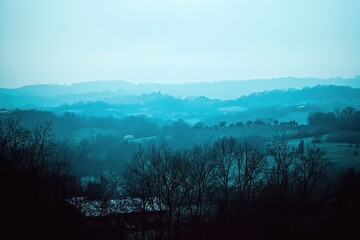 Serene teal landscape, rolling hills, misty, winter trees