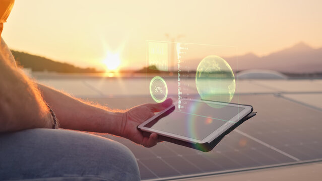 A man holds a tablet with a holographic display of a globe and data, symbolizing the integration of solar energy and technology.