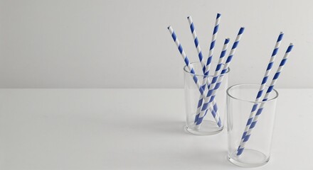 Striped straws displayed in clear glasses on a minimalist background  