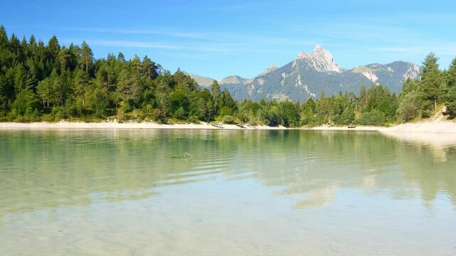Natural alpine lake Urisee near Reutte with transparent water, calm shoreline, and surrounding green hills in Tyrol
