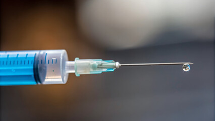 Vaccine booster Concept ,close up of syringe with droplet of liquid at tip, showcasing precision and readiness for use